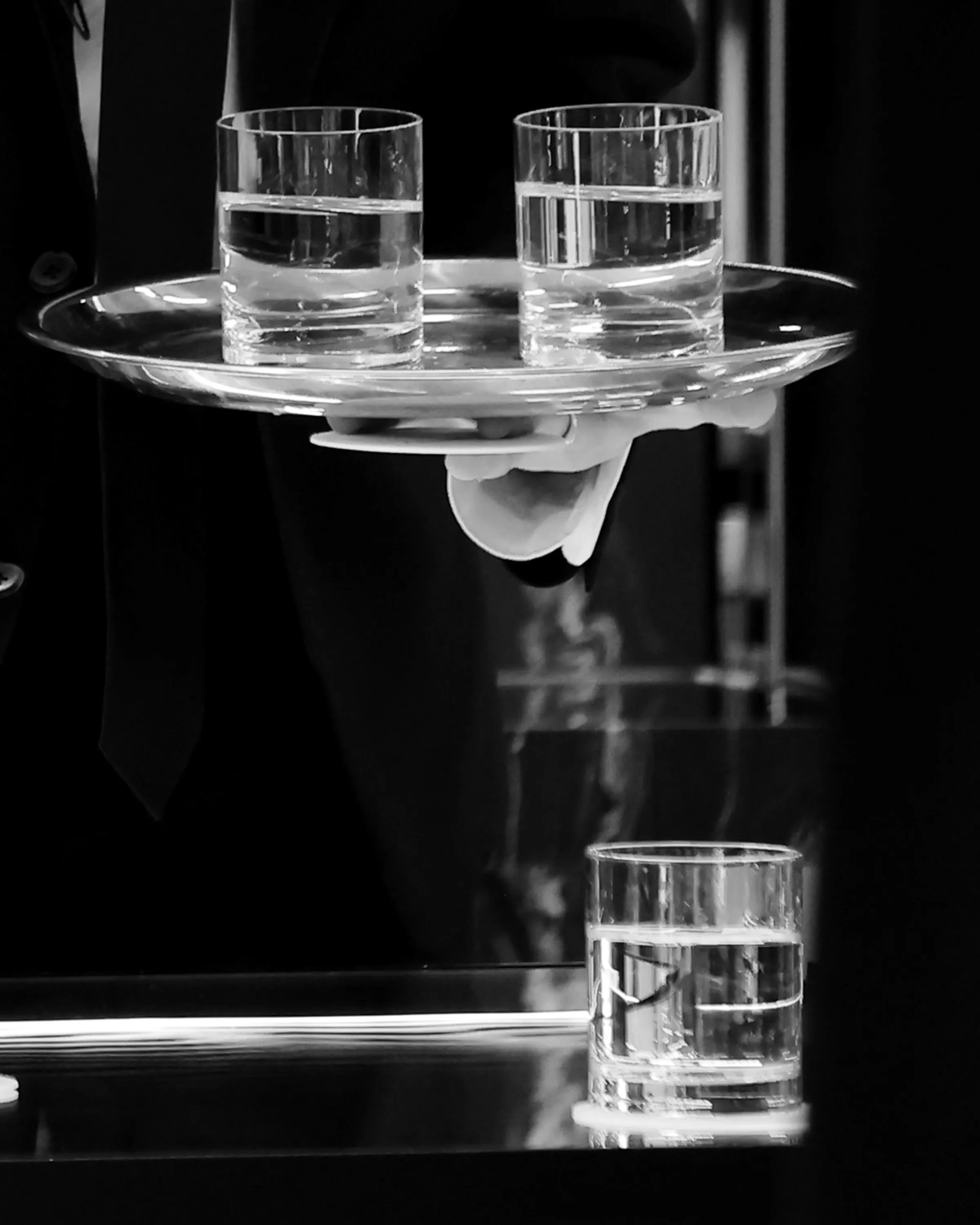 銀のトレーで水を運ぶスタッフの手元